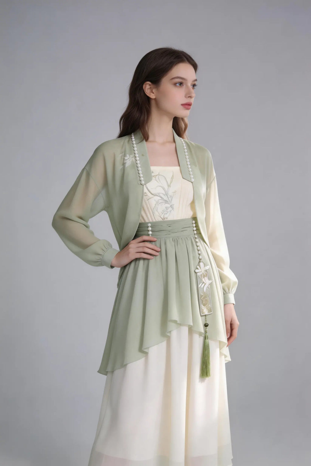 Woman wearing a Elegant Sage Green Chiffon Cardigan & Cream Dress Set - Modern Hanfu Inspired Two-Piece Outfit
 on a gray background