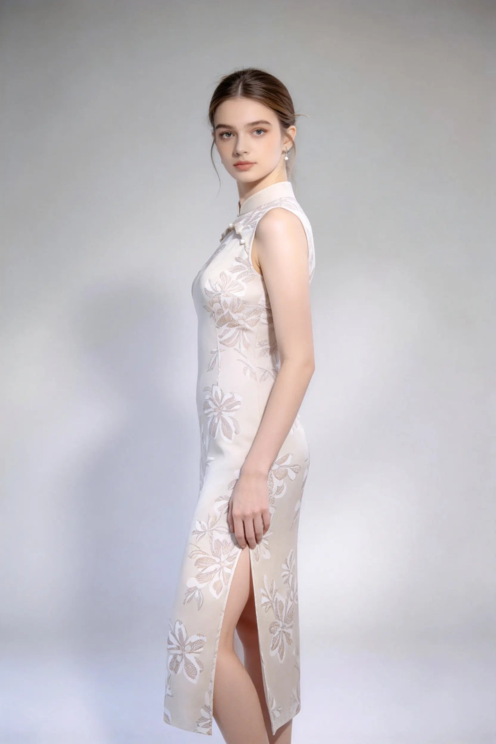 Woman wearing sleeveless floral embroidery cheongsam with cutout frog buttons, double-lined mandarin collar qipao dress against a plain background