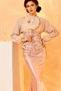 Woman wearing a traditional outfit with a floral top and pink skirt against a yellow background