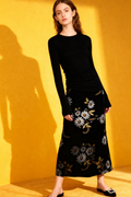 Woman wearing a black dress with floral patterns against a yellow background